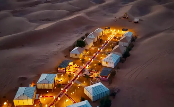 Aerial view of a luxury Sahara desert camp illuminated with warm lanterns at night during a 3 days desert tour from Fes to Marrakech.